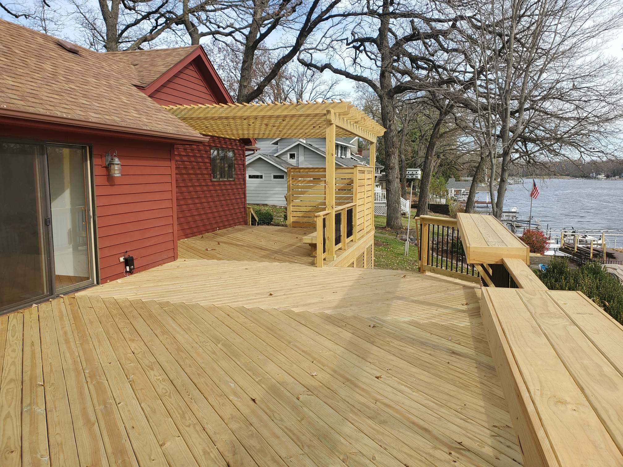 Stunning wood deck with built in bar, privacy fence, and pergola in Crystal Lake, overlooking the water.